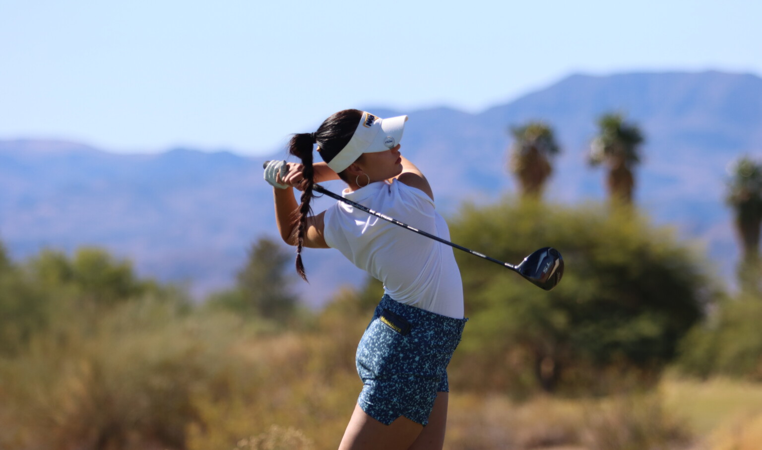 Northern Arizona University female student athlete golfing in desert region in front of mountains Northern Arizona University female student athlete golfing in desert region in front of mountains