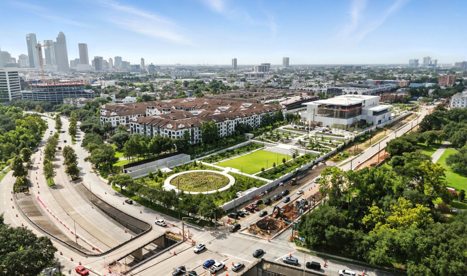 An aerial view of the Ismaili Center Houston on Allen Parkway, framed by gardens and green lawns with downtown in the distance.