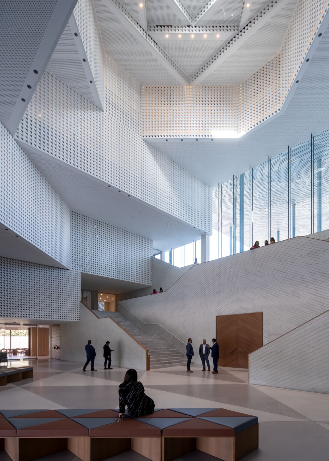 The Islamic architectural feature eivan that serves as the interior atrium with dramatic geometric cut outs angling the ceiling; perforating walls create visual interest and allow for natural light to fill the space; iwan