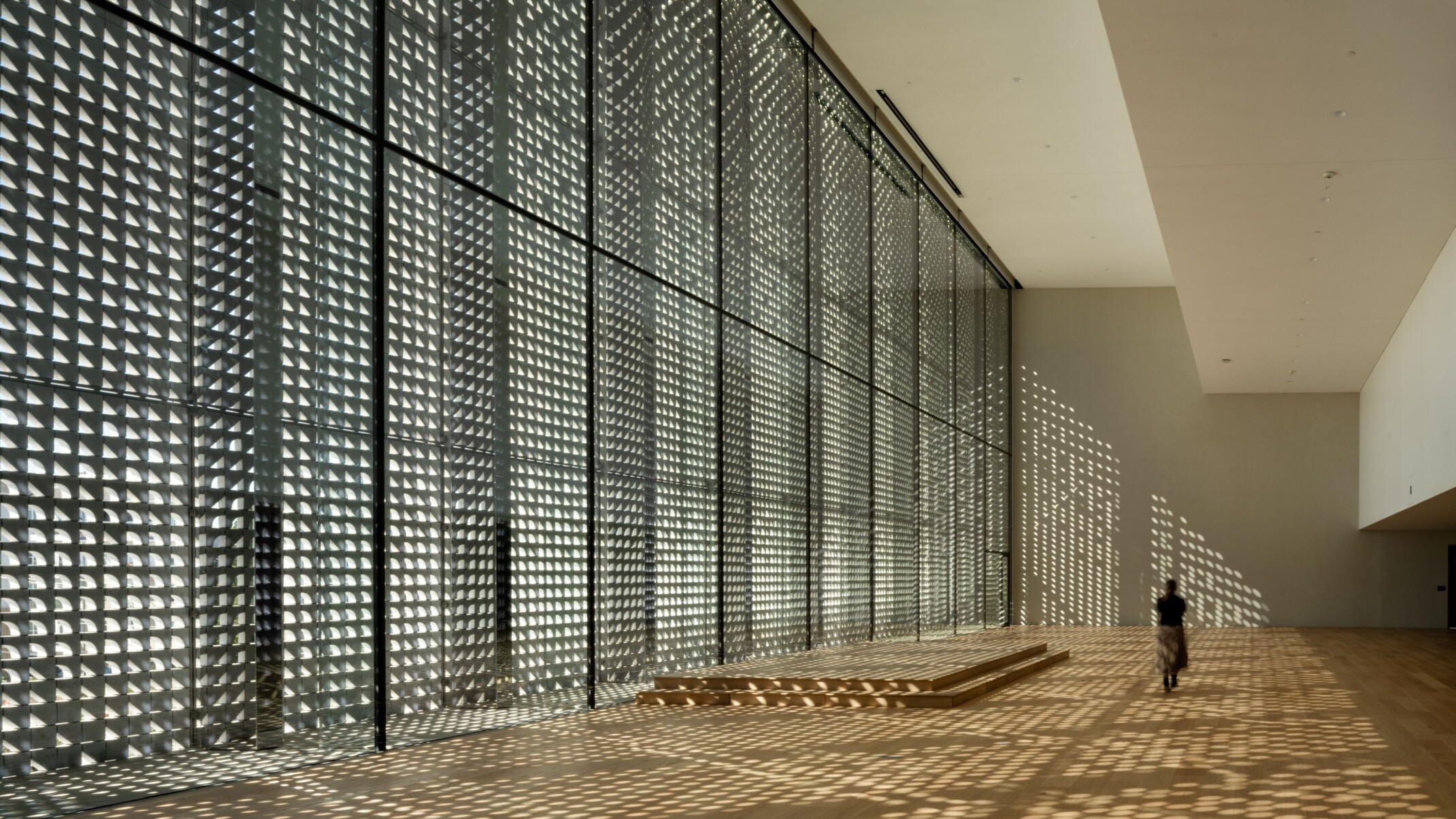 Photo by Nic Lehoux; Dappled light fills lobby of the United States first Ismaili Center; woman walks through the double height calming space