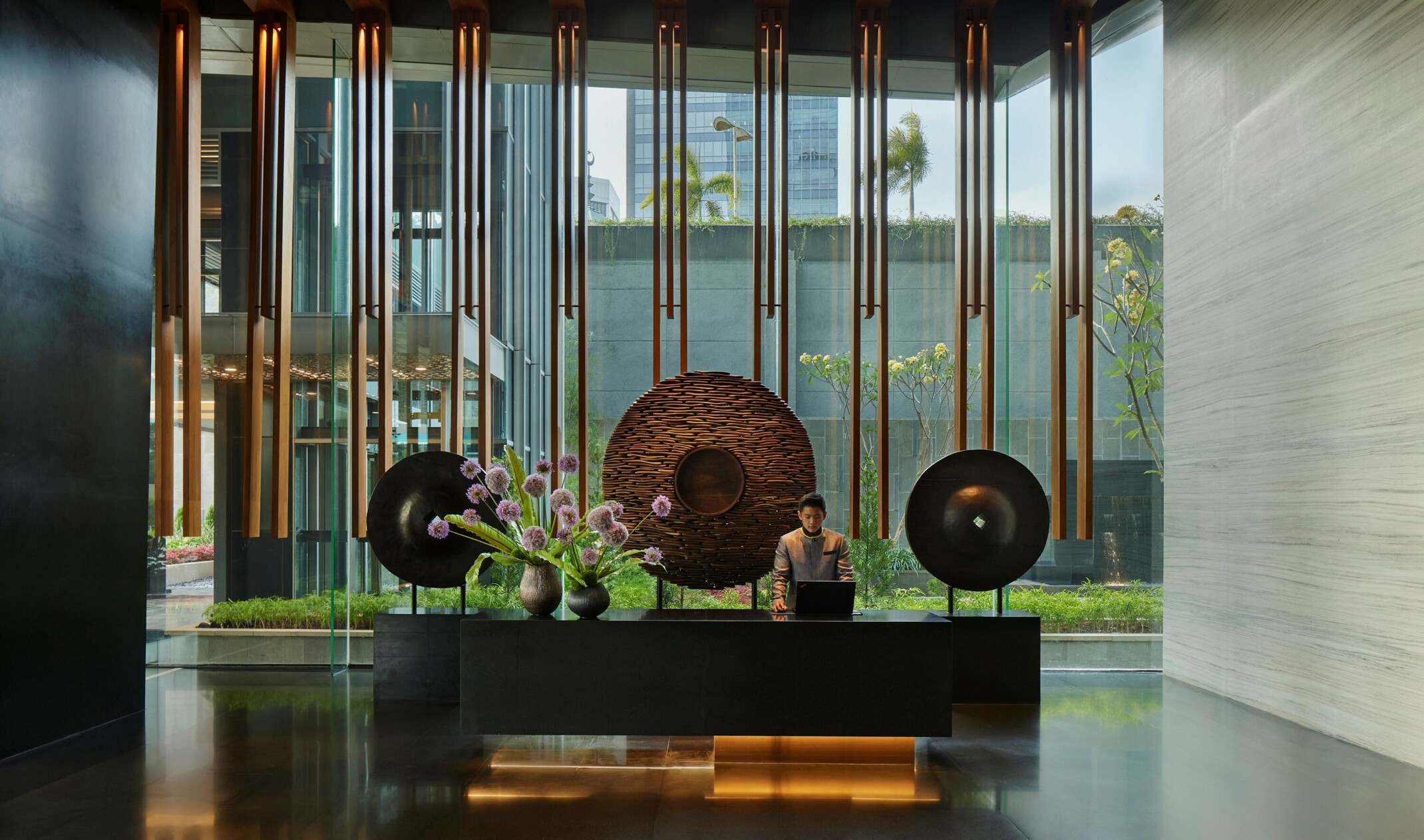 minimalist circular art against floor to ceiling windows behind a modern hotel lobby front desk; minimalist high design space
