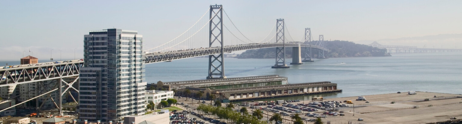 tall stand alone building in front of the bay bridge in San Francisco