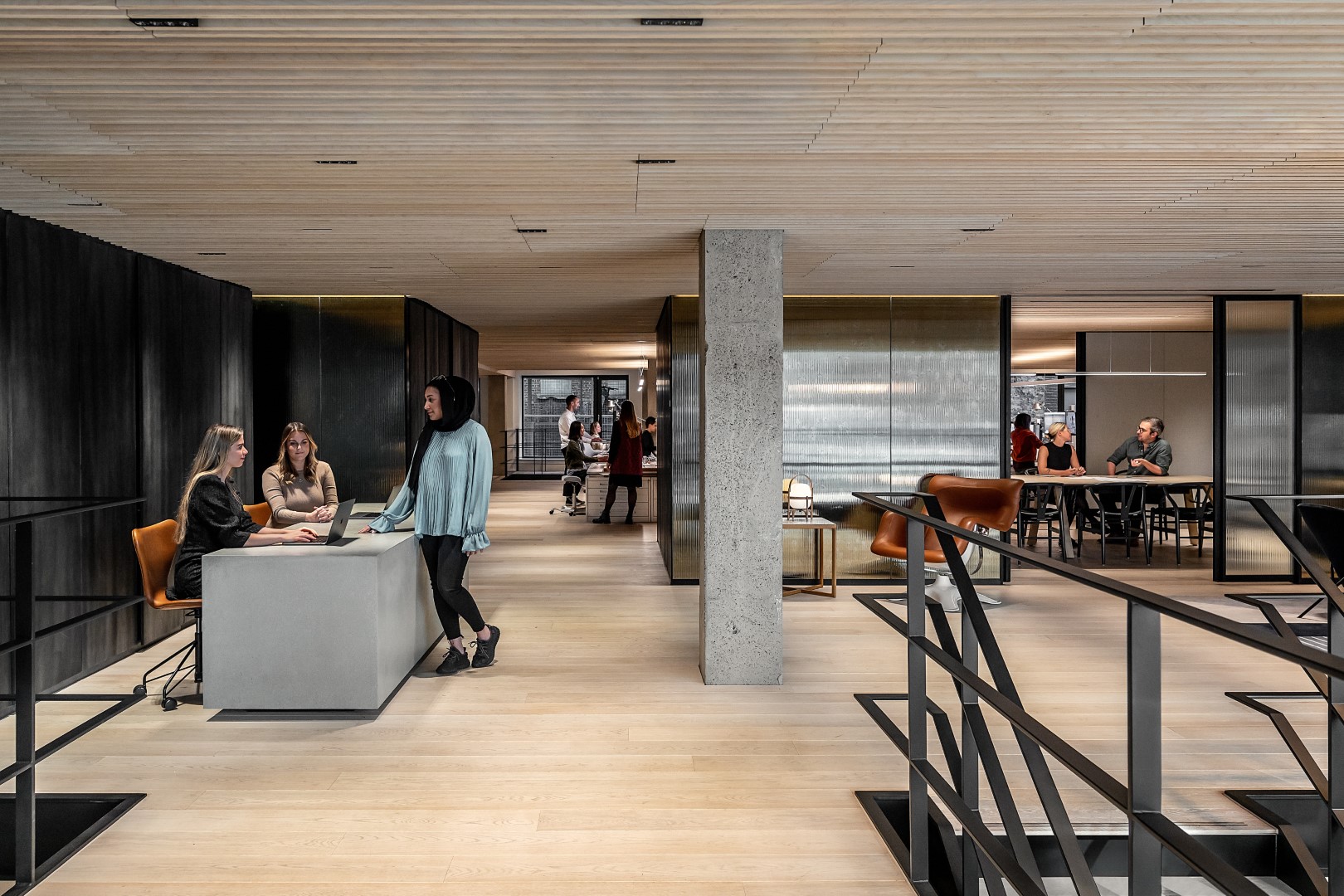 modern office space; varied working stations with sofa and counter seating; background work stations and coference rooms