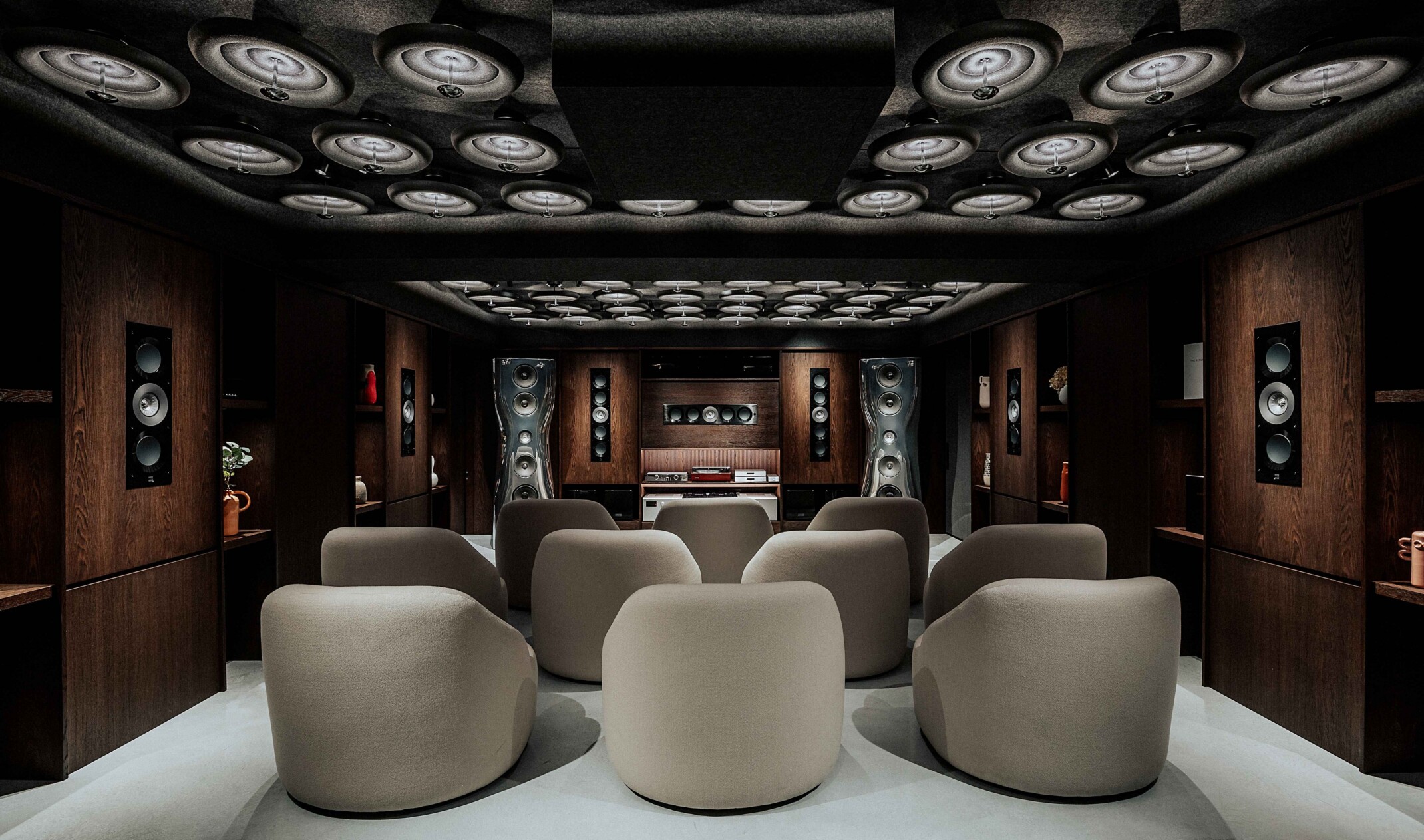 Comfy, sherpa sofa seats face a record mixing table and several speakers built into dark wood walls and shelving