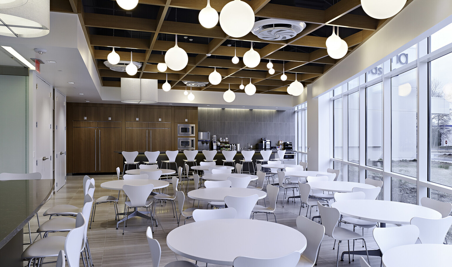 dining space with white tables and chairs, wood panel ceiling, and white round bulb pendant lighting dining space with white tables and chairs, wood panel ceiling, and white round bulb pendant lighting