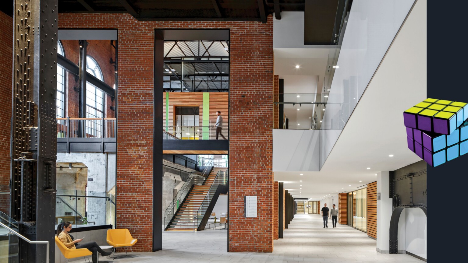 new South Street Station health education facility; restored brick; restored exposed beams with white and modern elements throughout; adaptive reuse of abandoned building; rubiks cube graphic on the right side of image