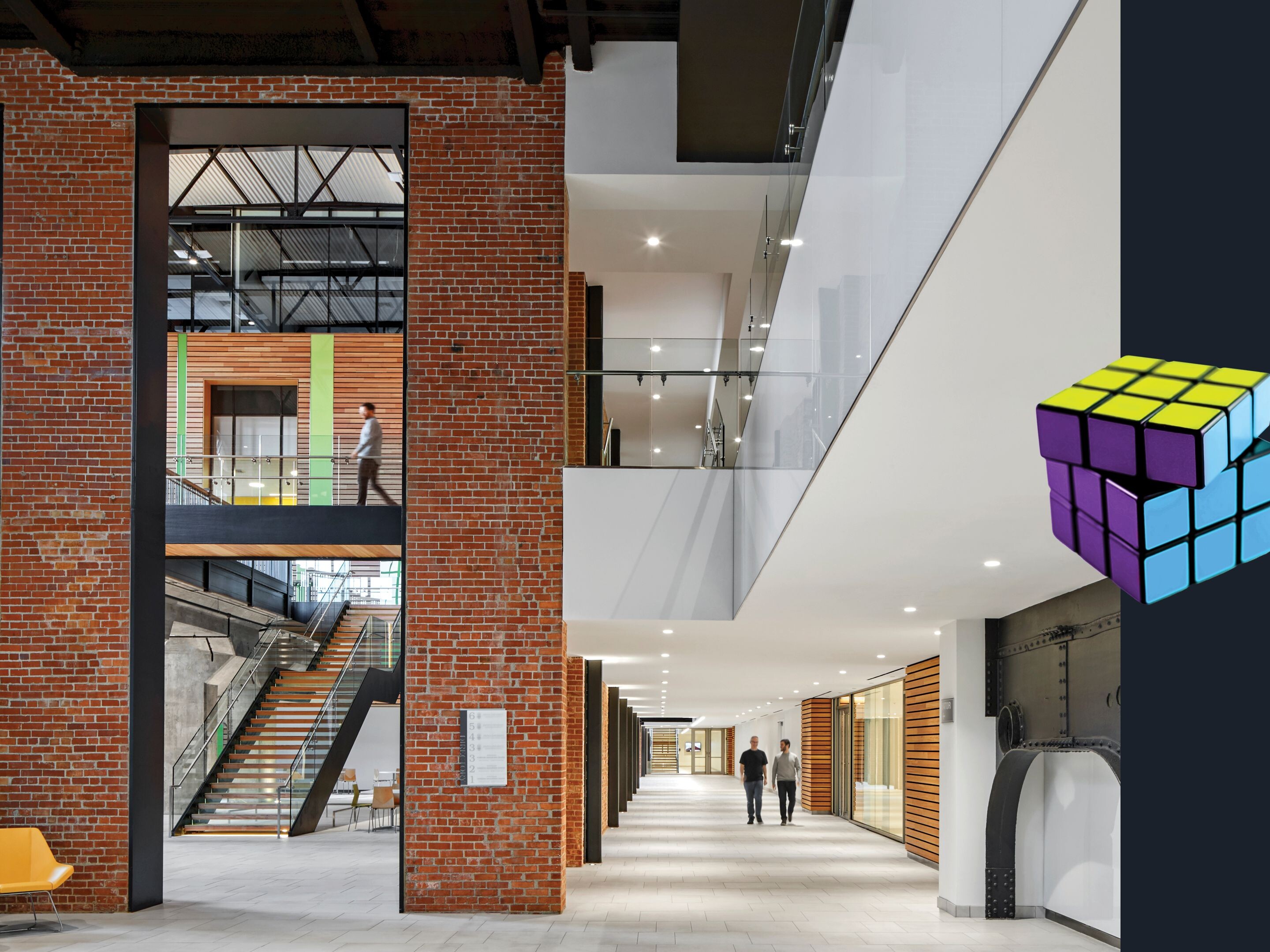 new South Street Station health education facility; restored brick; restored exposed beams with white and modern elements throughout; adaptive reuse of abandoned building; rubiks cube graphic on the right side of image