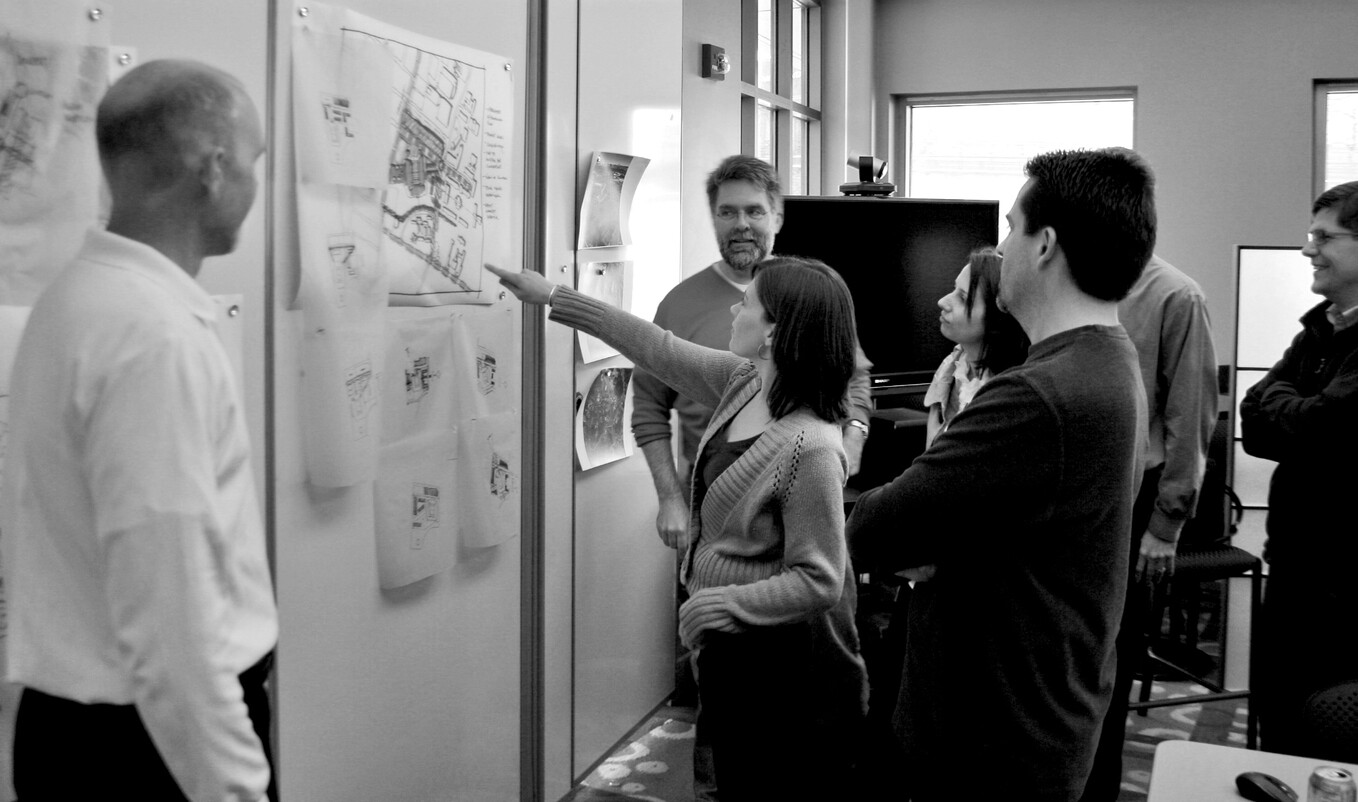 a design team critiques a pin up wall of concepts on trace paper