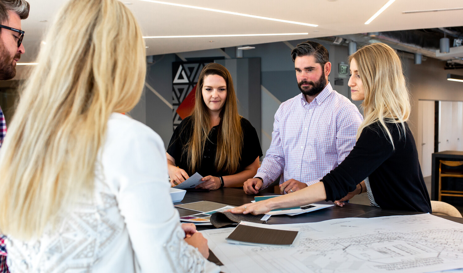 a group of young men and women working with a table top full of material finishes