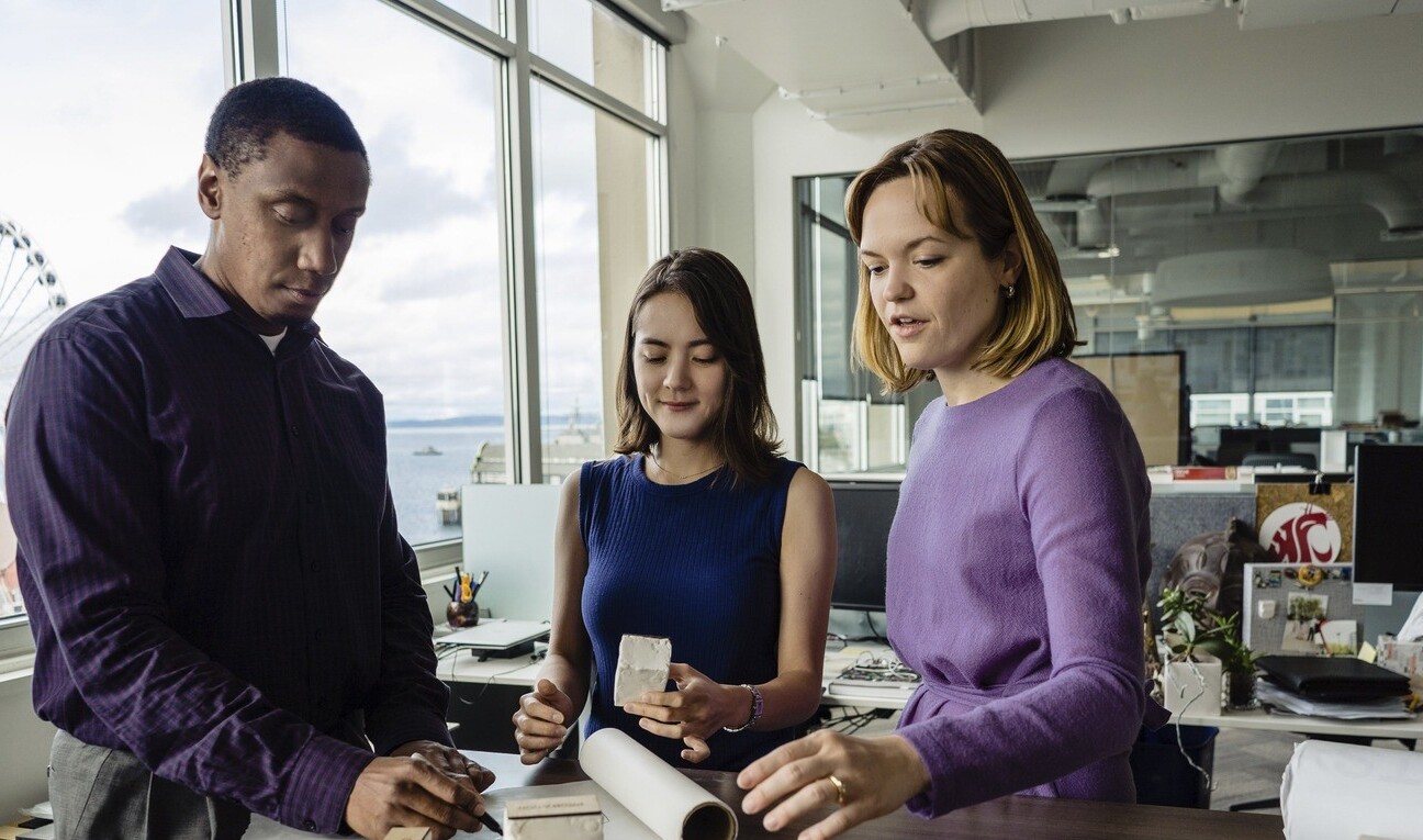 three design professionals around a building model