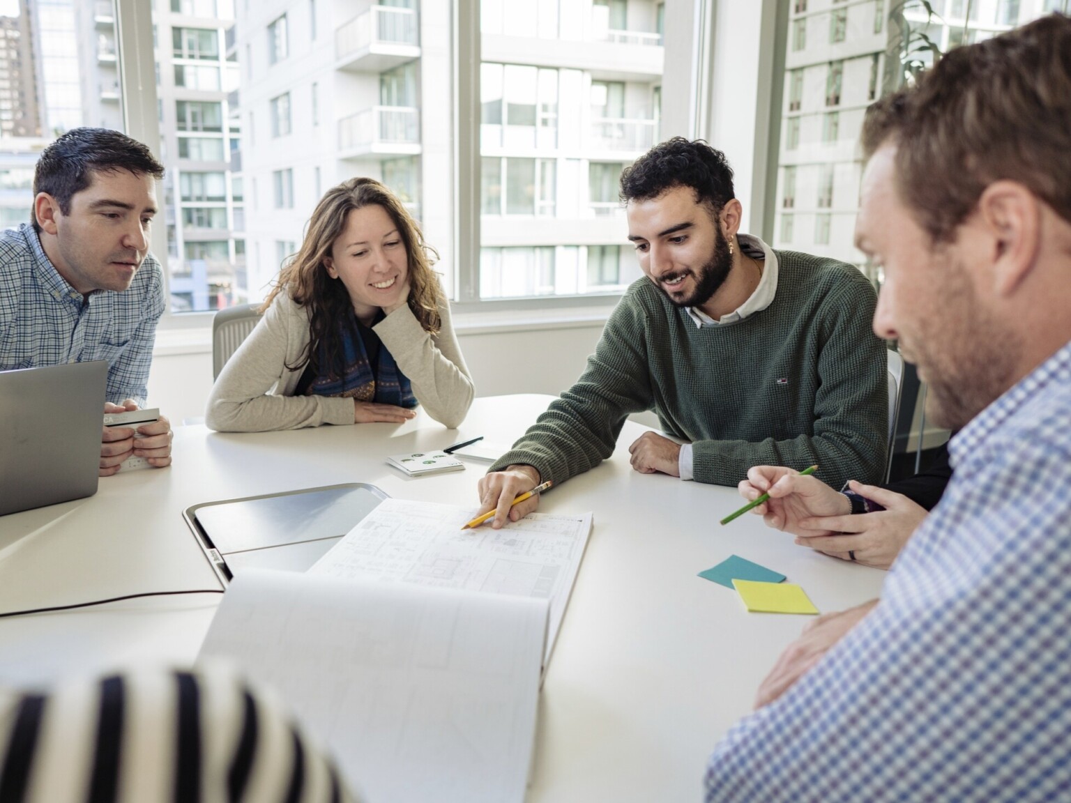 Group of Architects and Planners collaborating on a building project in a large, 22nd floor loft space with floor-to-ceiling windows on all sides, affording a 360 degree panoramic view of beautiful downtown Los Angeles