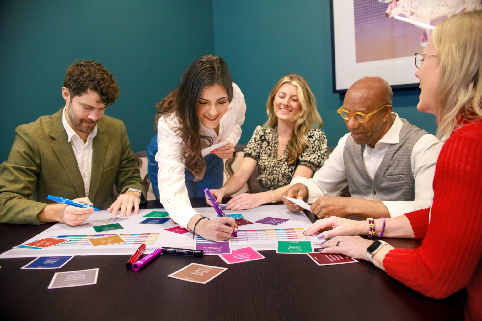 people huddled around a table with paper and sticky notes; collaboration