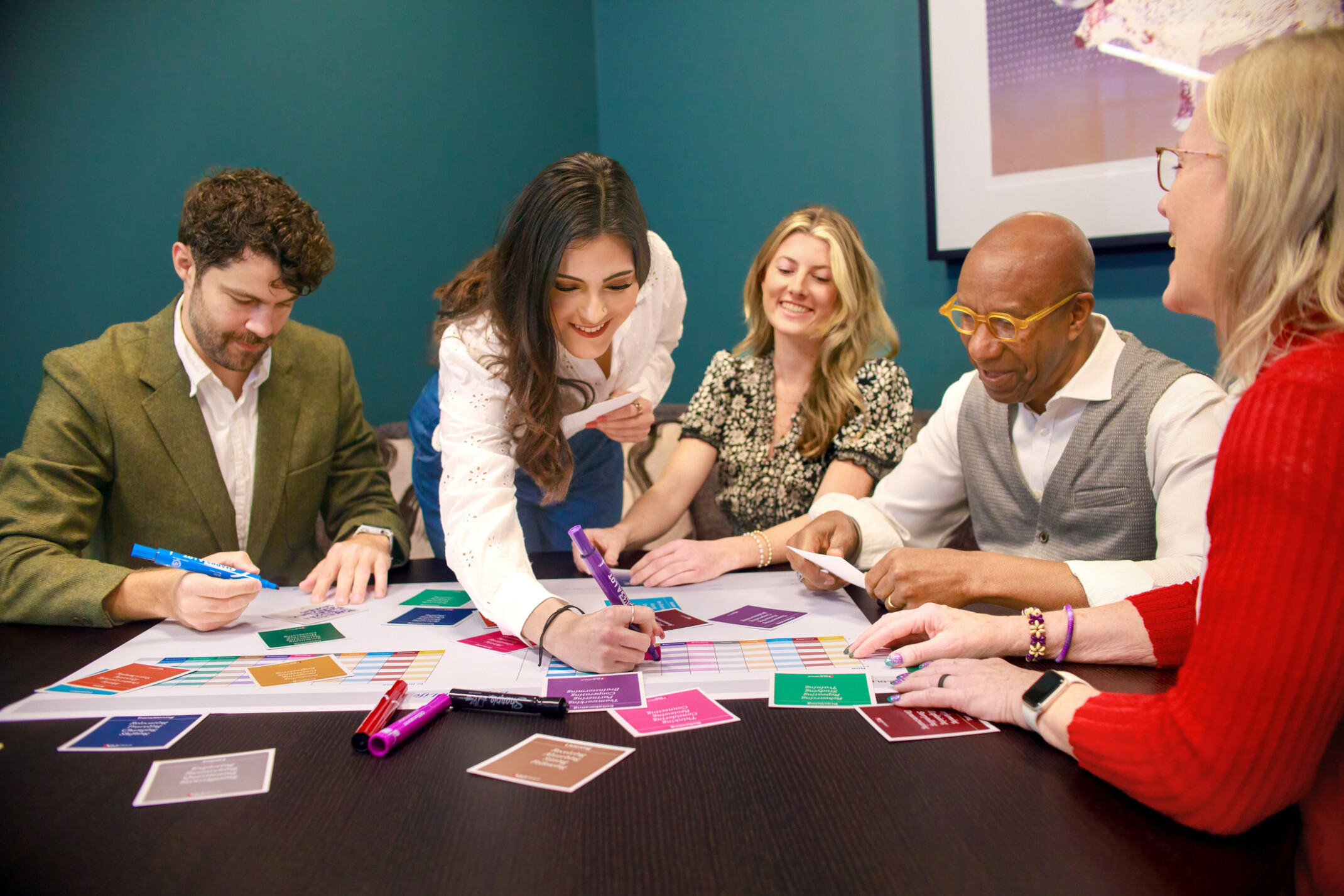 people huddled around a table with paper and sticky notes; collaboration