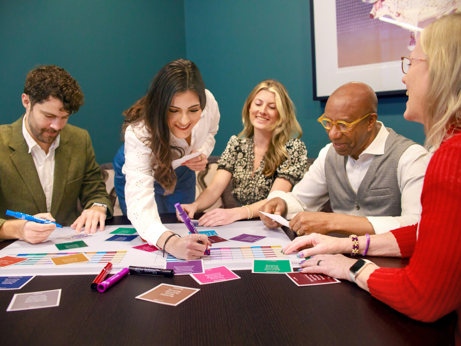 people huddled around a table with paper and sticky notes; collaboration