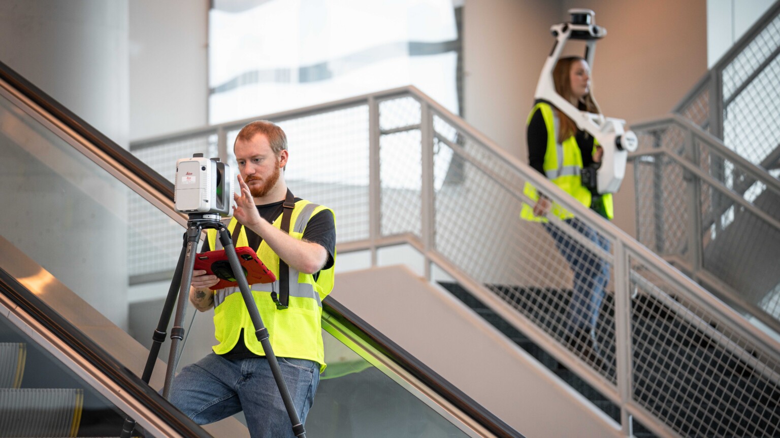 Two reality capture professionals working in a stairwell of a building with advanced cameras