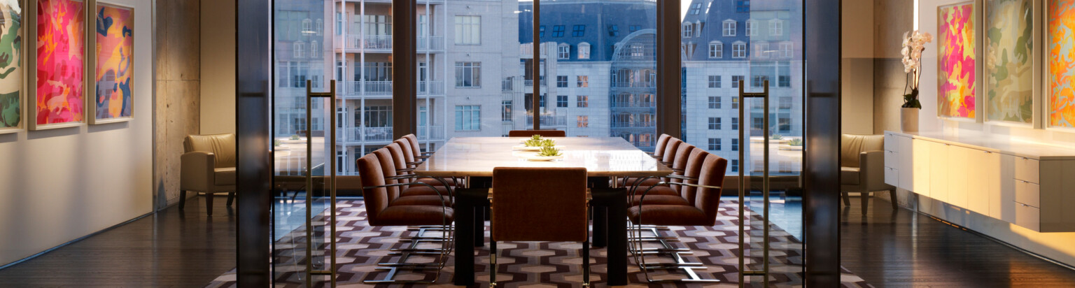 colorful conference room walls with a central feature table overlooking floor to ceiling windows to a cityscape