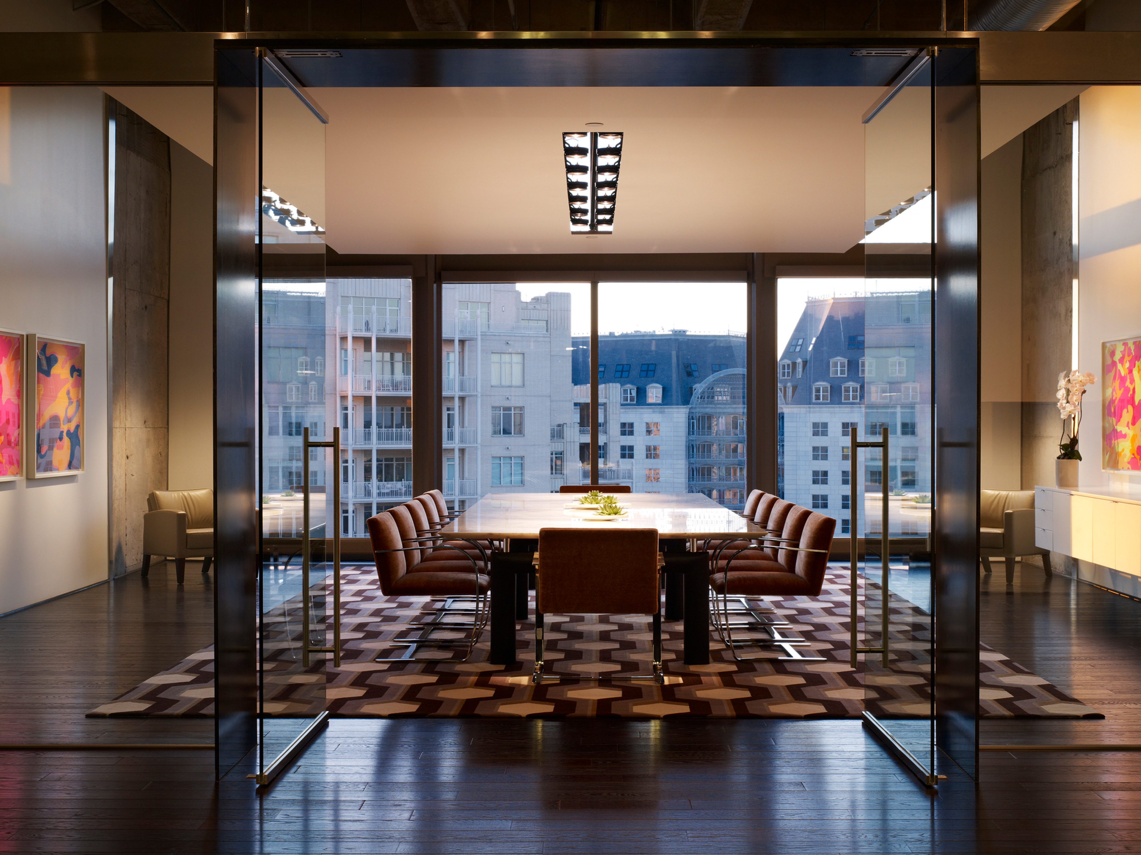 colorful conference room walls with a central feature table overlooking floor to ceiling windows to a cityscape