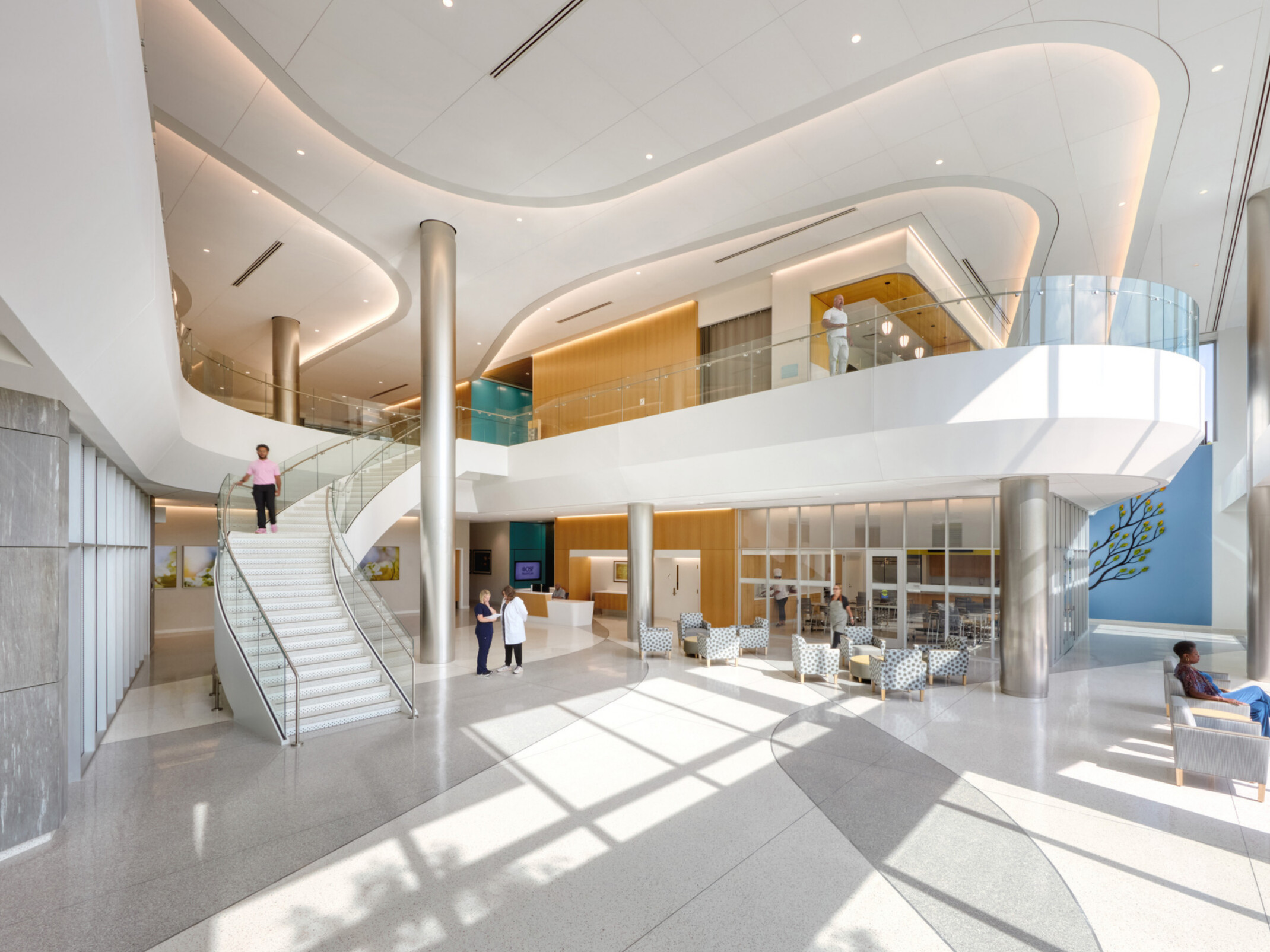 Inside image of OSF Cancer Institute and Proton Therapy; Modern, sleek and mostly white design with balcony and staircase down to the waiting area