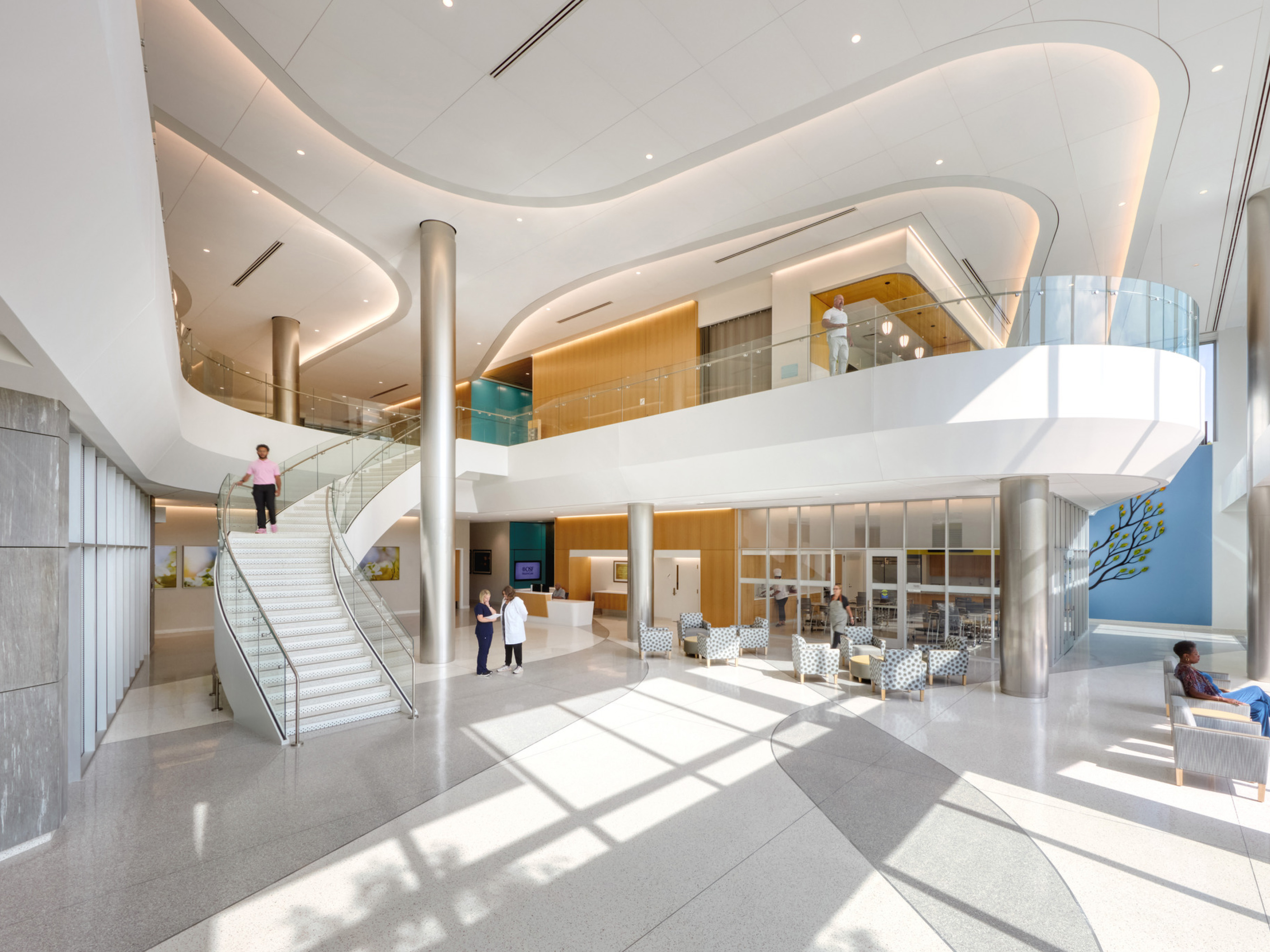 Inside image of OSF Cancer Institute and Proton Therapy; Modern, sleek and mostly white design with balcony and staircase down to the waiting area