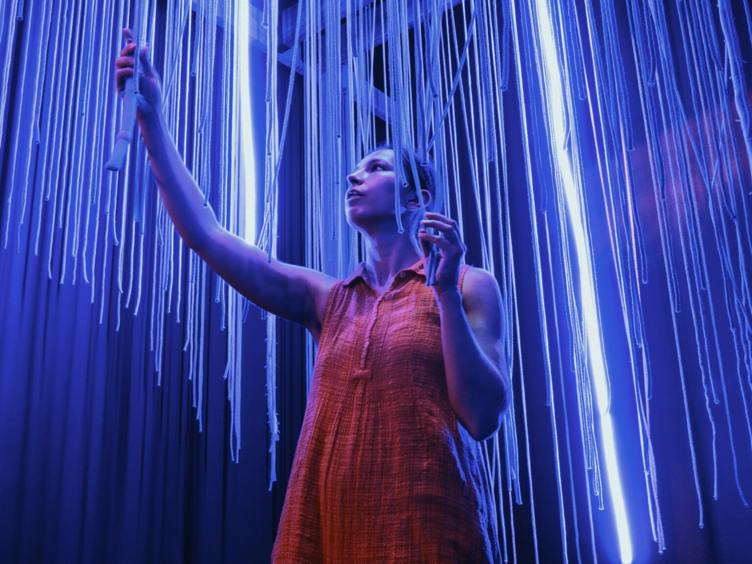 woman standing in a blue lighted room with tactile and sensory elements around her; camera shot from the ground up point of view