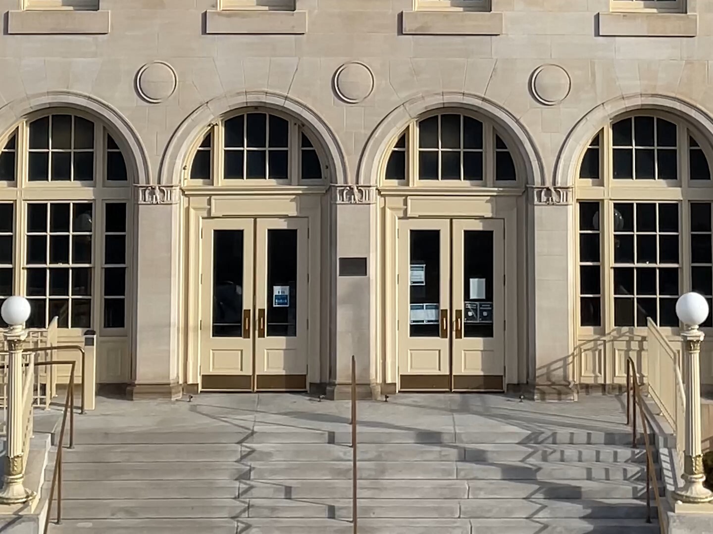 Front doors of a federal building, showing classical design with stone arches and steps leading up to the doors