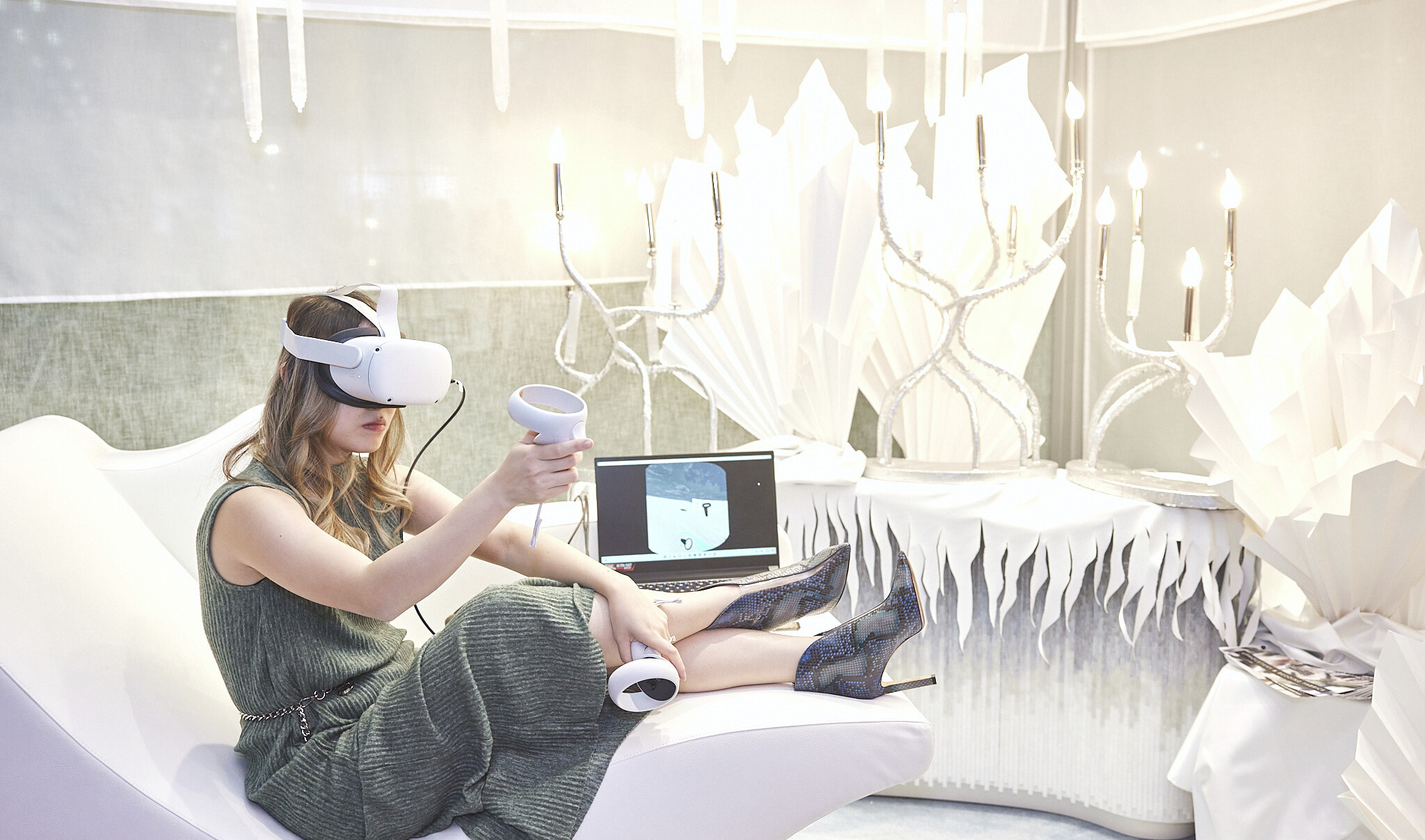 Woman uses virtual reality in all white wintery room with ice shard style sculptures and organically curving candelabra lights