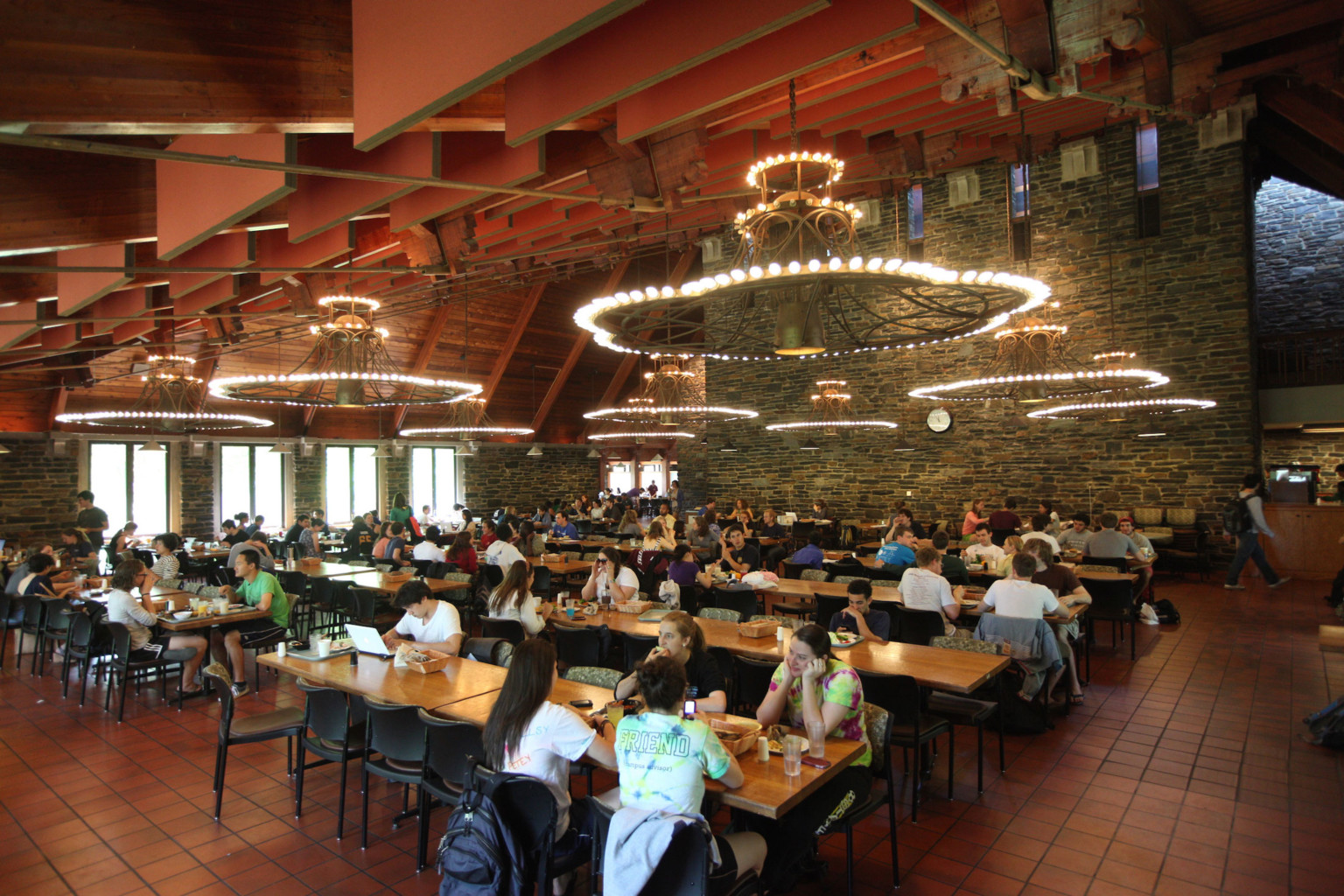 Sharples Dining Hall at Swarthmore College. Rows of tables under wood ceiling with panel accents and layered chandeliers