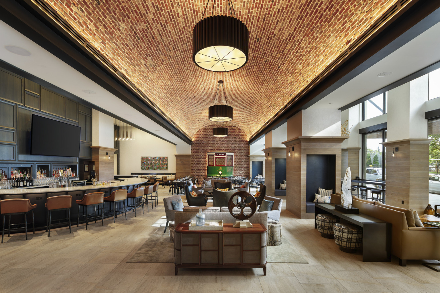 Lounge and bar at Canopy by Hilton Dallas Uptown with illuminated tile ceiling and large shaded pendant lamps, street view