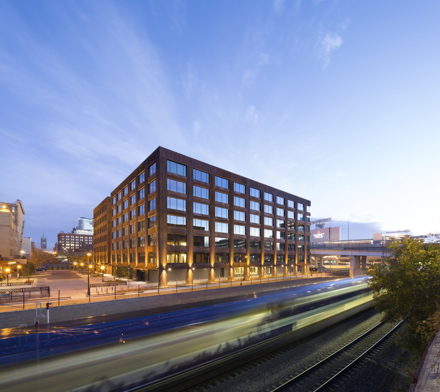 Hines T3 Partnership building in Minneapolis, a mass timber midrise building illuminated at night viewed from across highway Hines T3 Partnership building in Minneapolis, a mass timber midrise building illuminated at night viewed from across highway