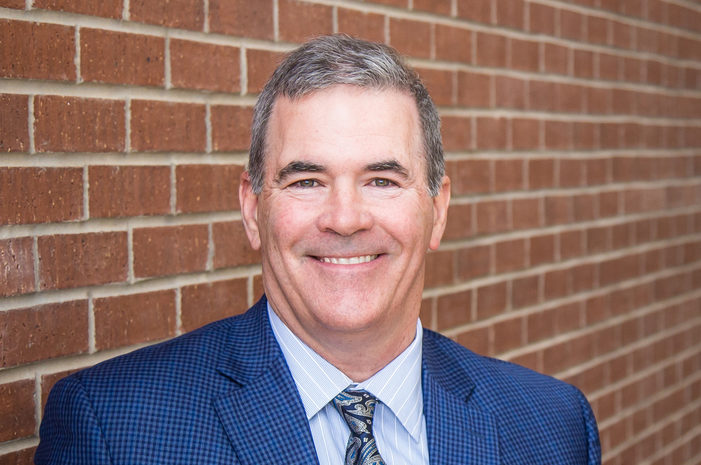 smiling man in a blue suit jacket and a blue paisley tie