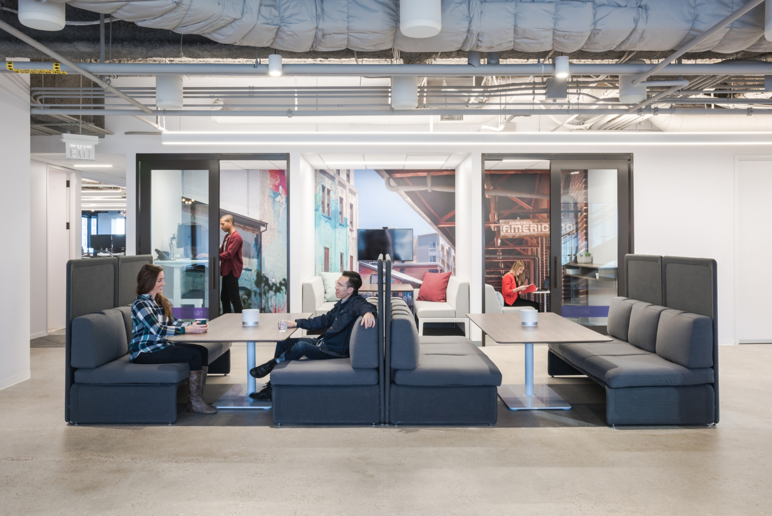people working at booths with private phone booths and large graphic murals people working at booths with private phone booths and large graphic murals