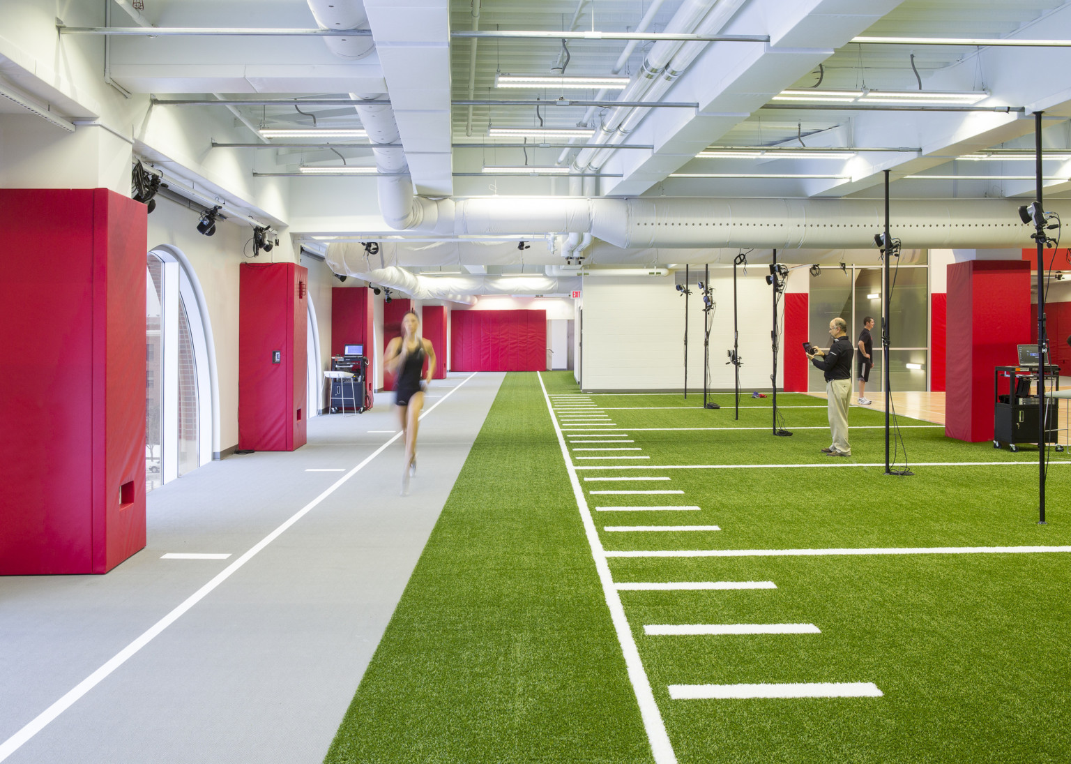 The University of Nebraska Athletic Performance Lab training facility with grey and turf floor in white room with red padding