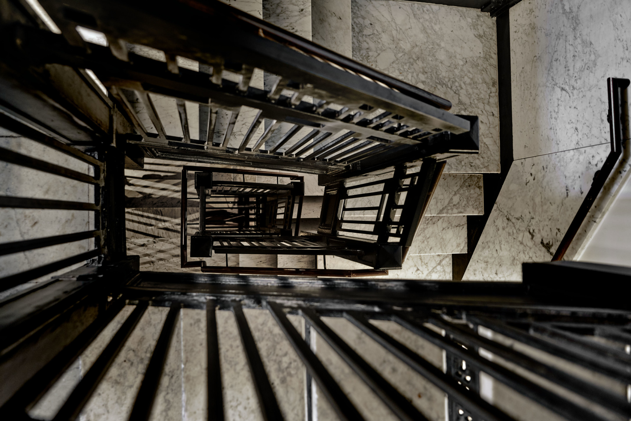 the view down a black wrought iron and marble staircase the view down a black wrought iron and marble staircase
