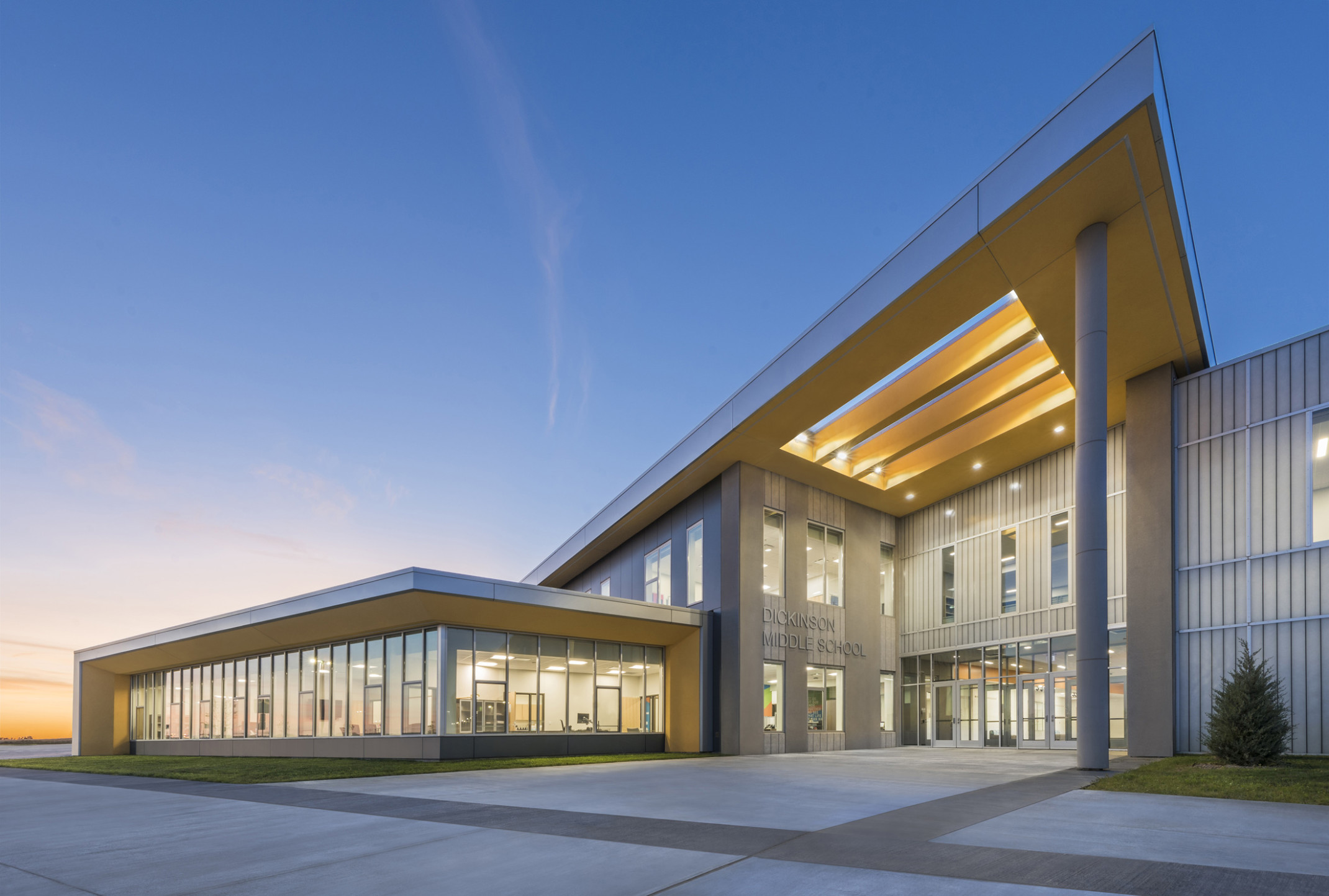 Dickinson Middle School, a grey panel building with skylight canopy and glass extension to left with wrapped facade Dickinson Middle School, a grey panel building with skylight canopy and glass extension to left with wrapped facade