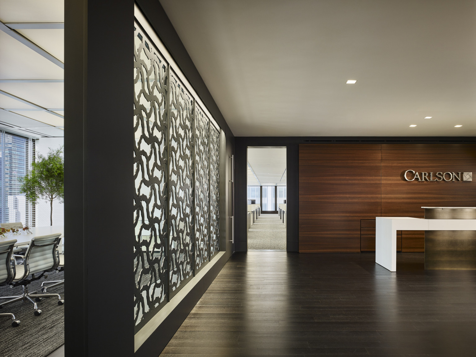 Carlson Capital New York office white reception desk with gold accent in wood room. Partition, left, with organic cutouts