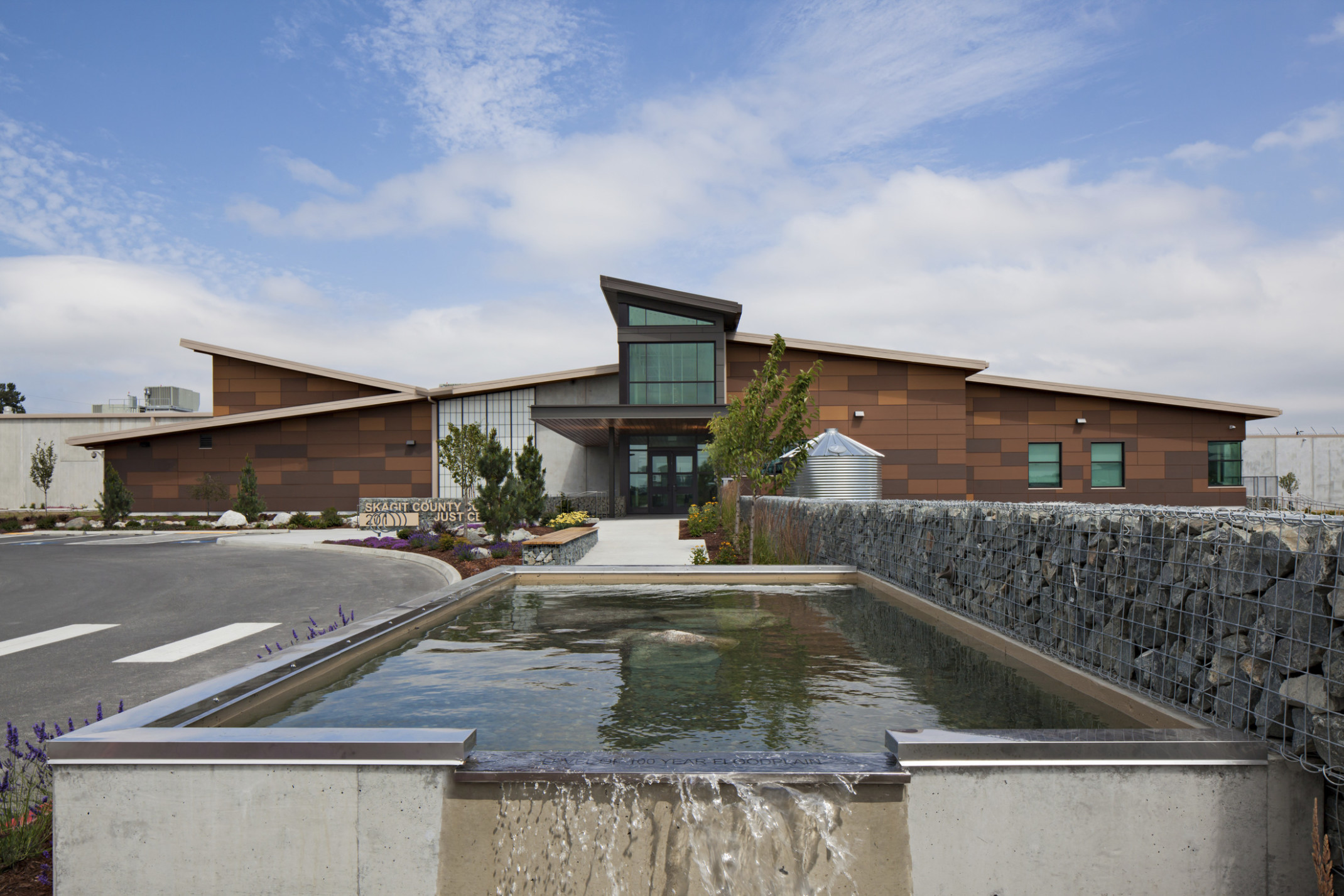 The Skagit County Community Justice Center, a stone building with central entryway. Front is water feature and stone gabion