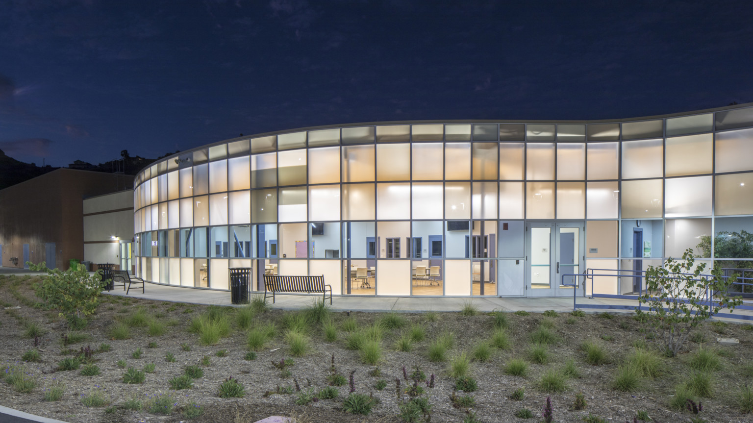 exterior view of the youth facility at night with bright square windows on the building exterior view of the youth facility at night with bright square windows on the building