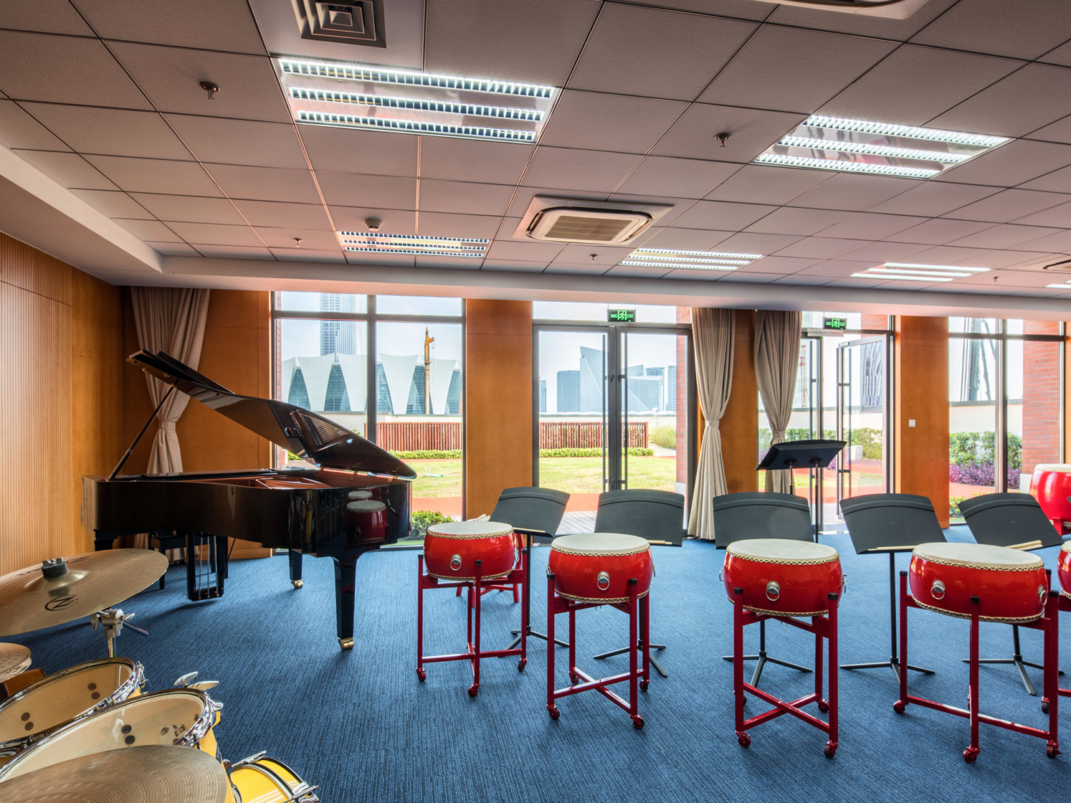 music room with piano, drum set, and single red drums at Huili International School