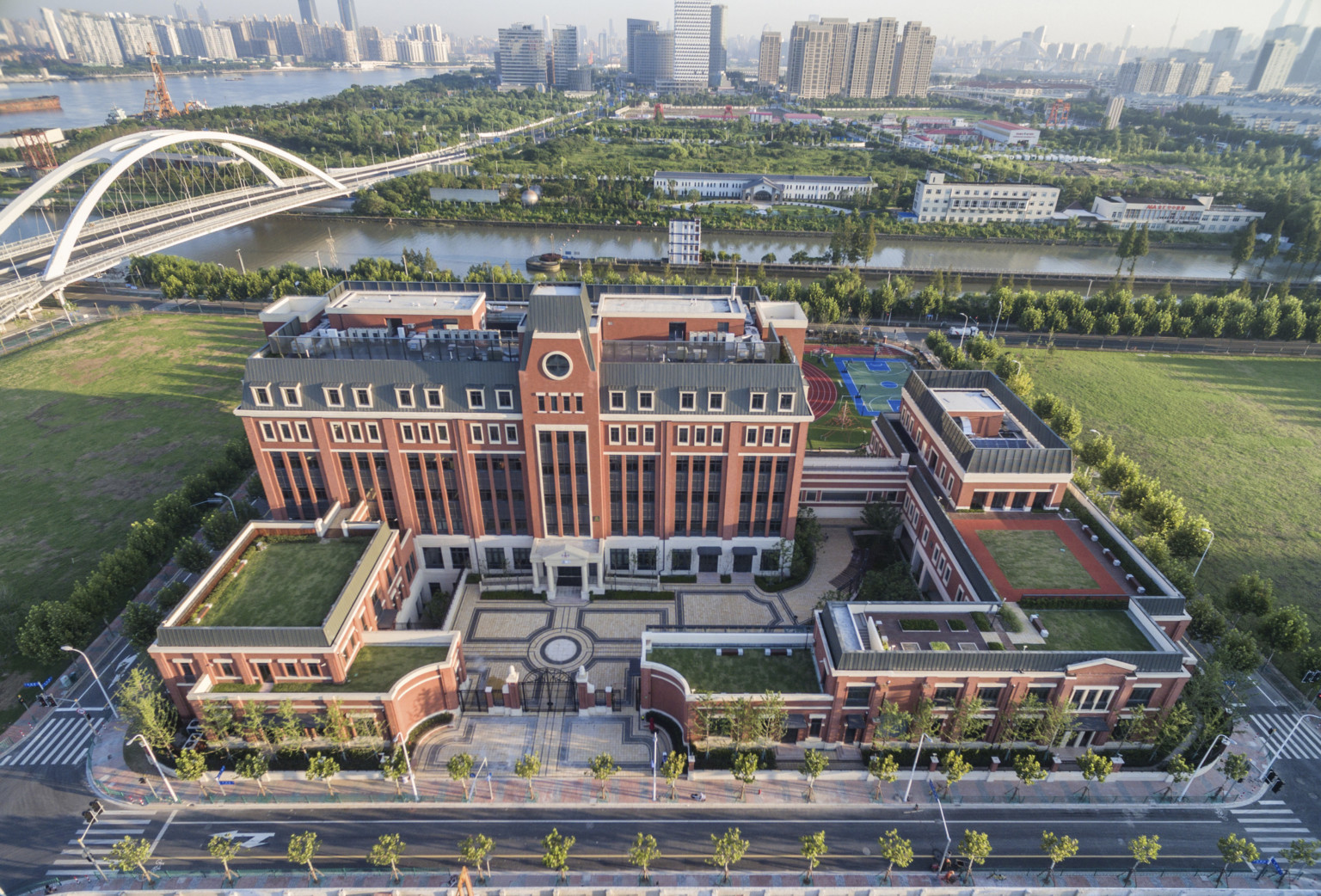 Aerial view of Huili campus from front. A gated stone courtyard is surrounded by brick buildings with living roof sections