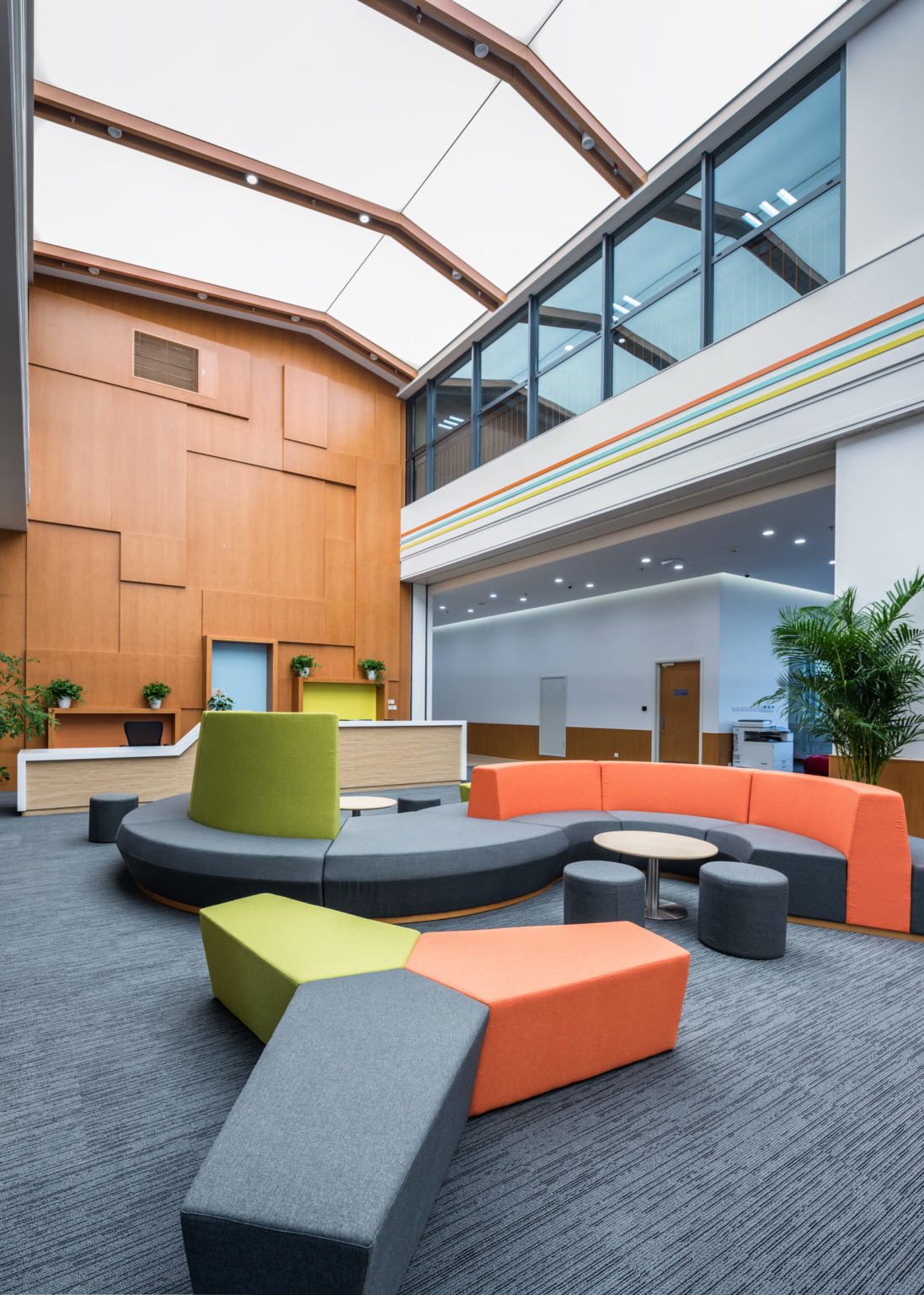 orange and green lounge seating in a high-ceiling room at Huili International School
