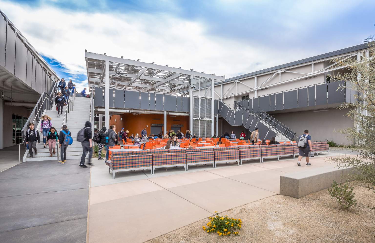 an outdoor learning area filled with orange seating shaded by solar canopies