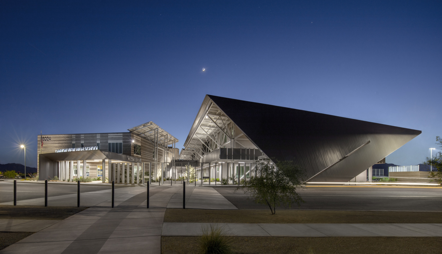 modern steel building with exposed structural beams and solar canopies illuminated at night