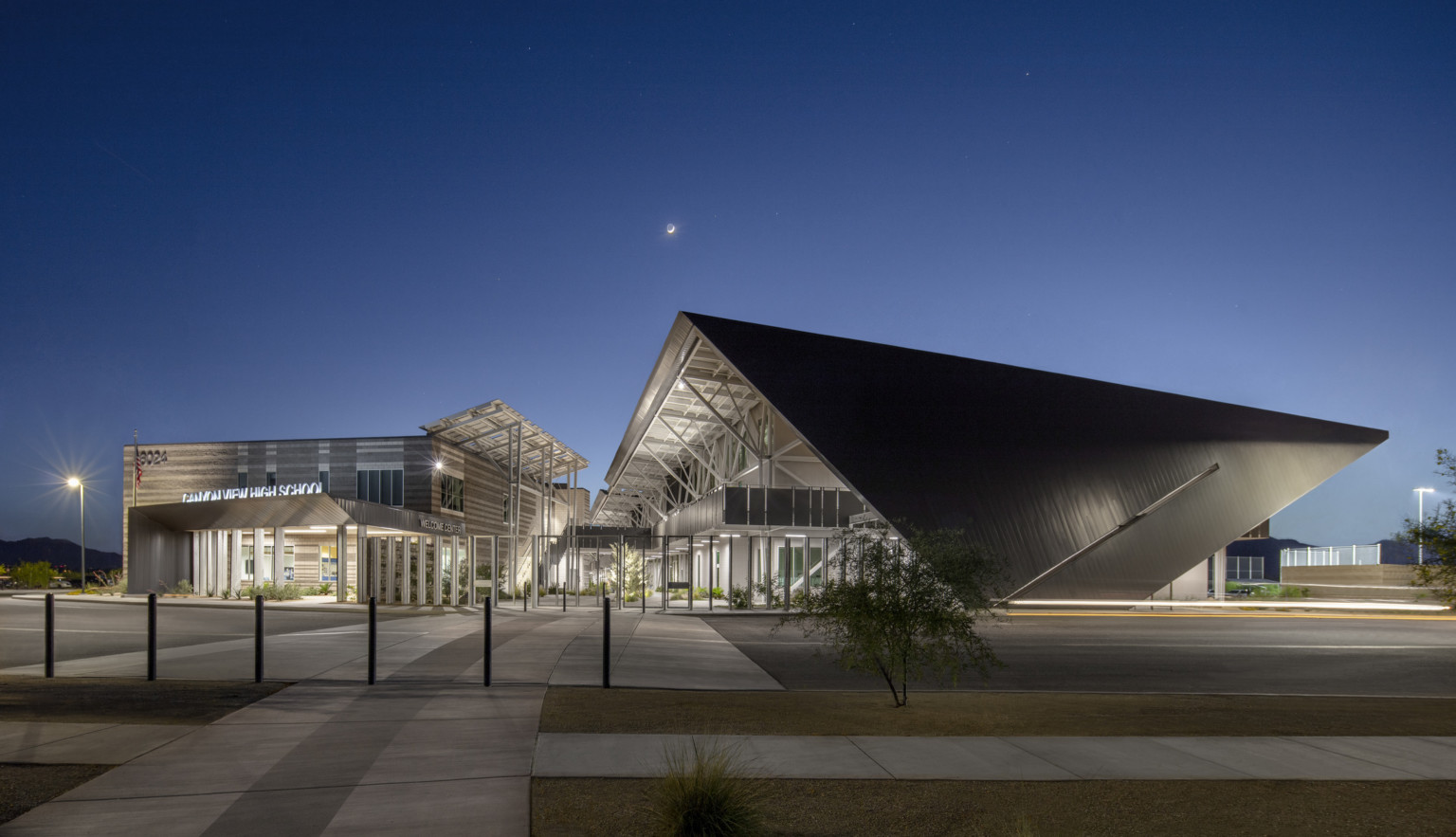 Modern steel building with exposed structural beams and solar canopies, night photography, steel roof, school, high school