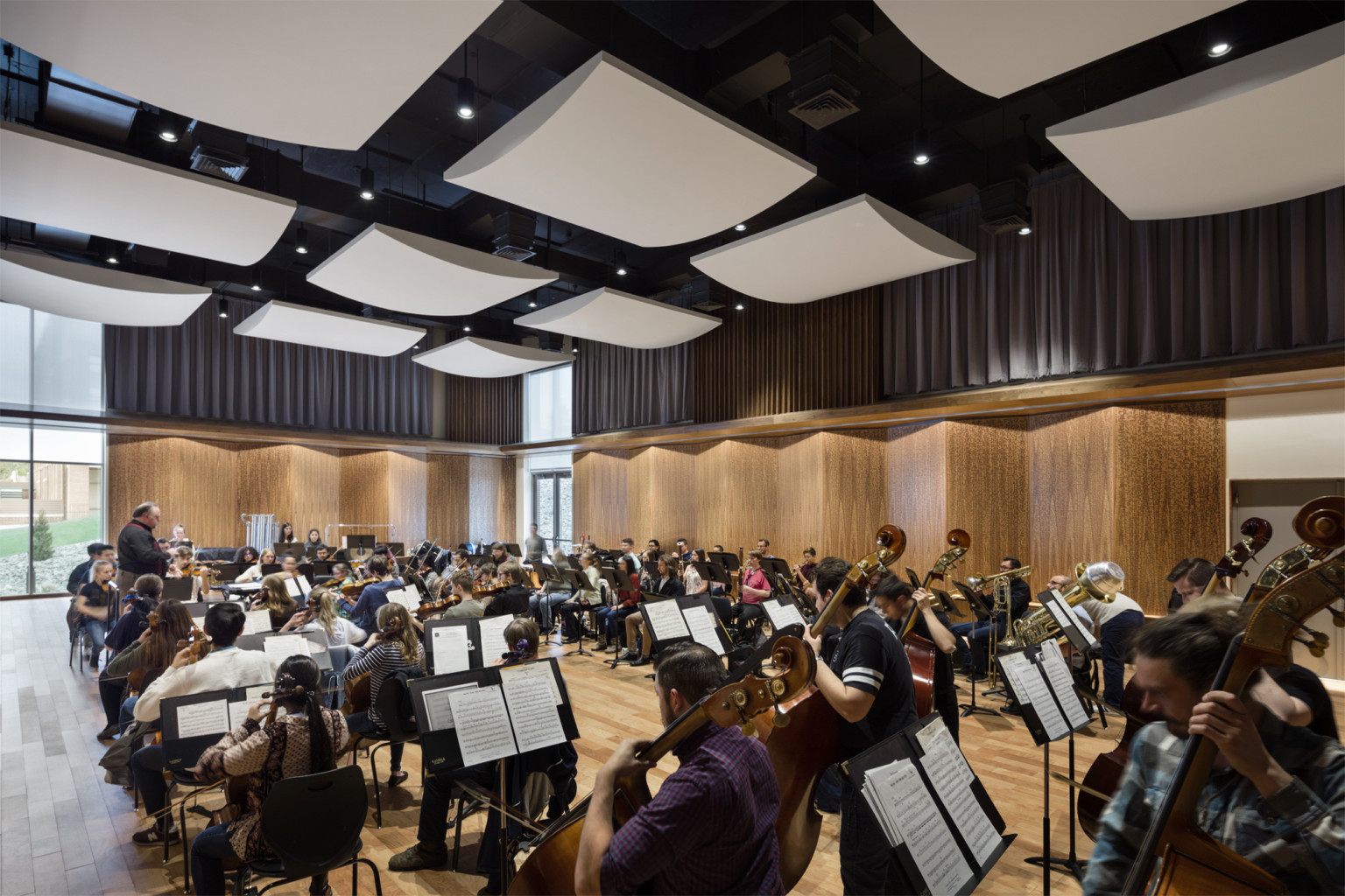 Student musicians rehearsing in studio with angled wood panels on the walls and white acoustical sound panels on the ceiling