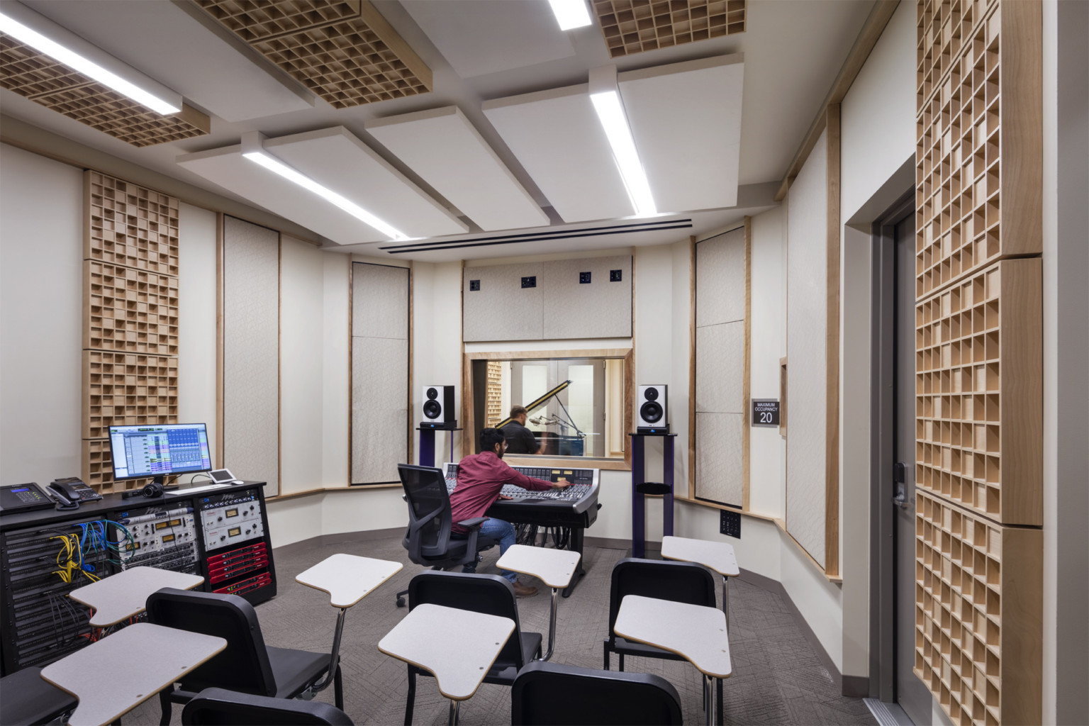 Student working in recording studio with white and wood panels on walls and ceiling