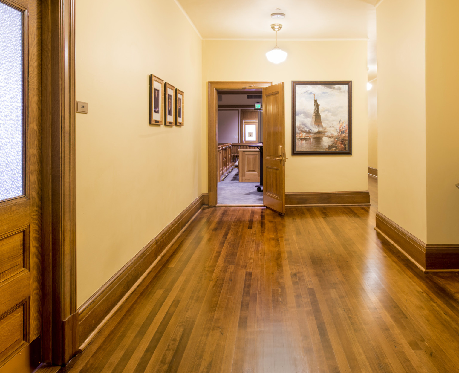 Cream colored walls along a winding hallway with hardwood floors and matching doors and baseboards
