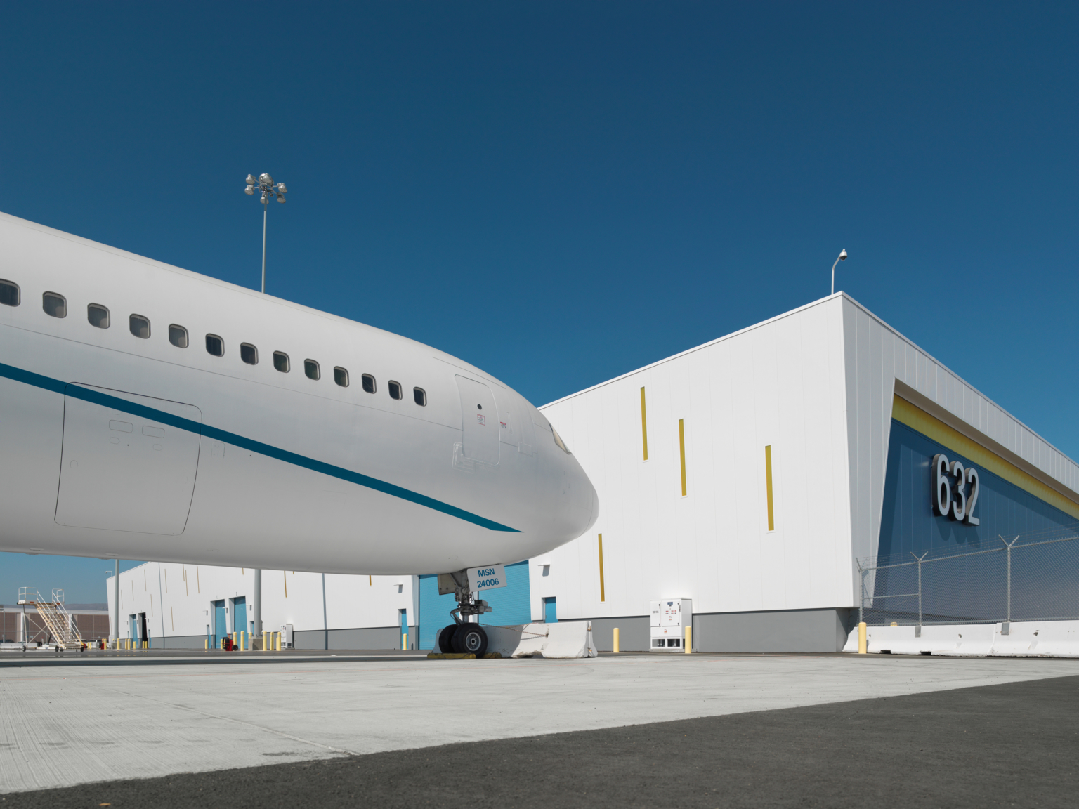 front of a large white plane pulled up to a white and blue cargo building