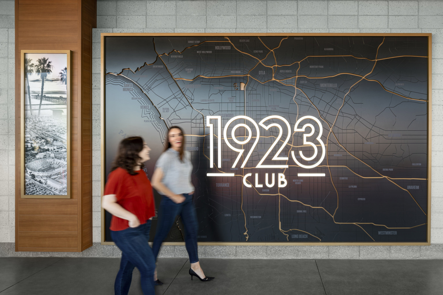 1923 Club logo illuminated in custom wall art engraving of Los Angeles map in gold frame on grey block wall. wood accent left