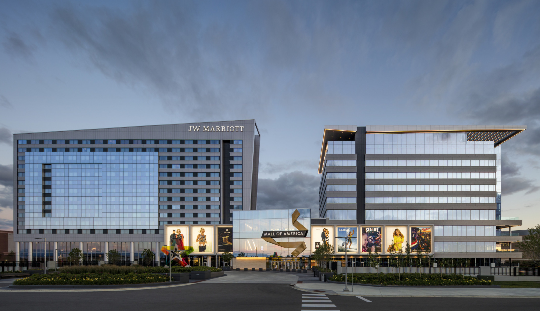 two modern glass buildings connected by a glass cube with large advertising billboards in front two modern glass buildings connected by a glass cube with large advertising billboards in front