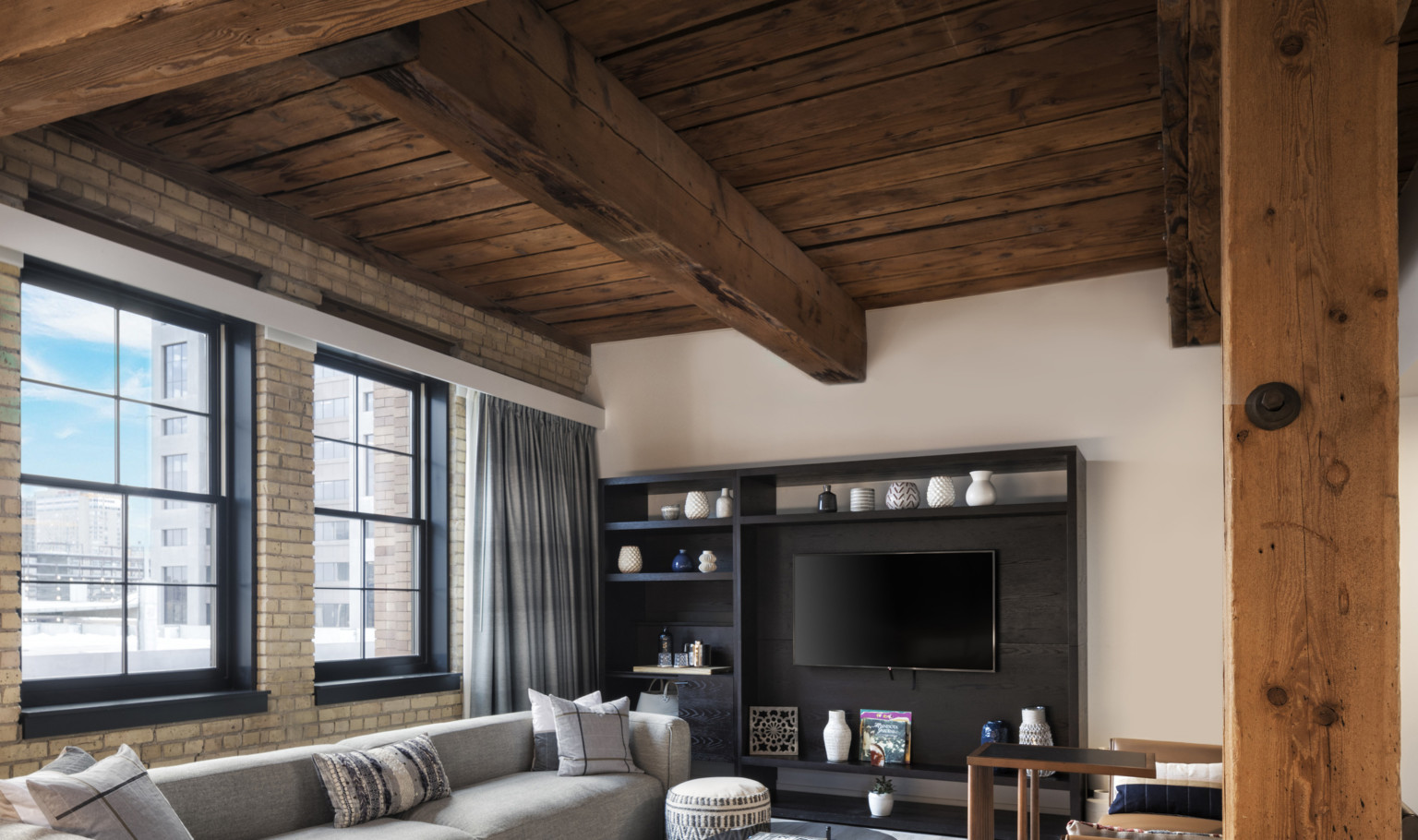 Heavy timber ceiling, beams, and columns with a gray sofa and dark wood entertainment center